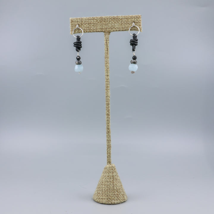 handmade aquamarine, larvakite, and black spinel leather & sterling silver earrings on a linen display hanger