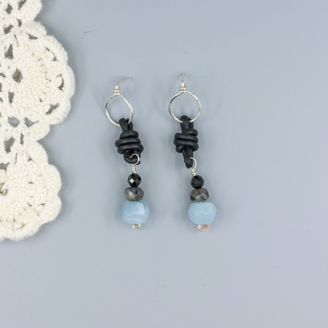 handmade aquamarine, larvakite, and black spinel leather & sterling silver earrings on a gray background