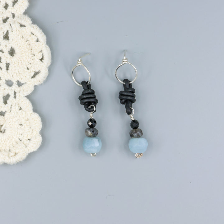 handmade aquamarine, larvakite, and black spinel leather & sterling silver earrings on a gray background