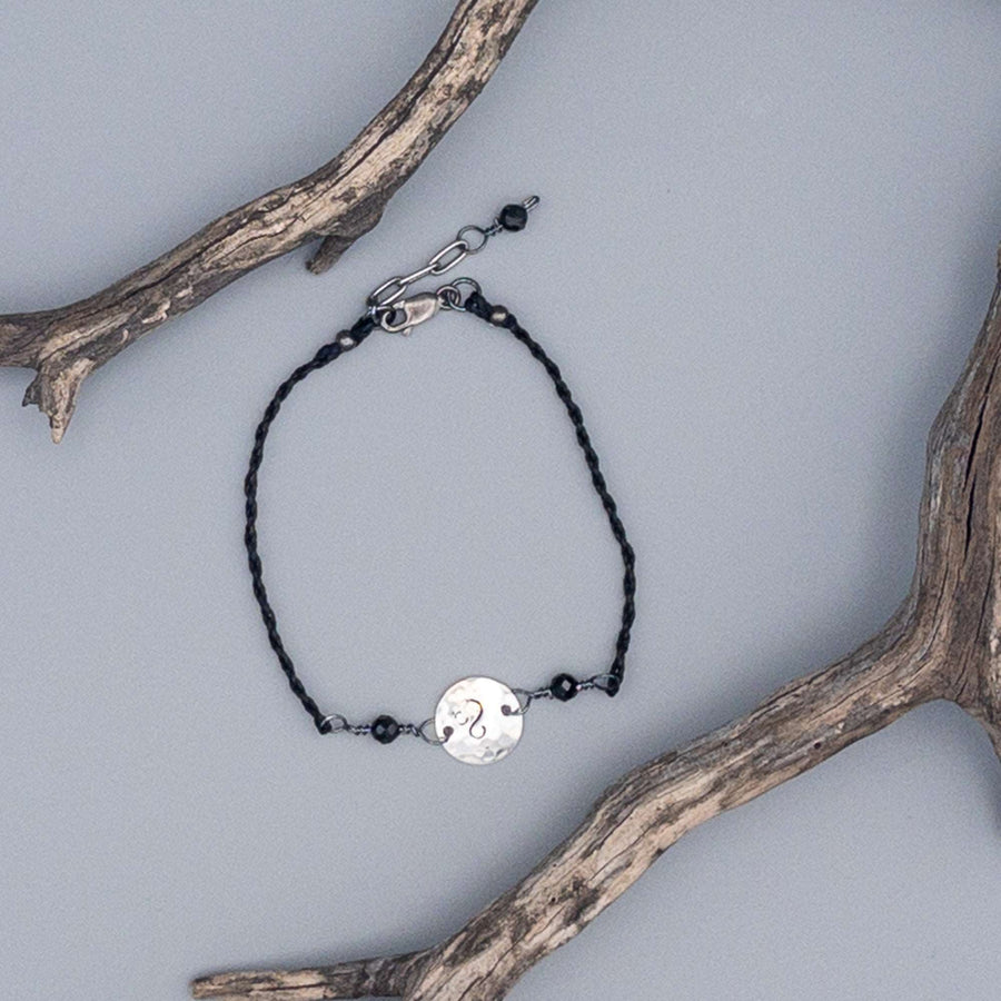 Silver Leo stamped bracelet with black spinel beads on gray