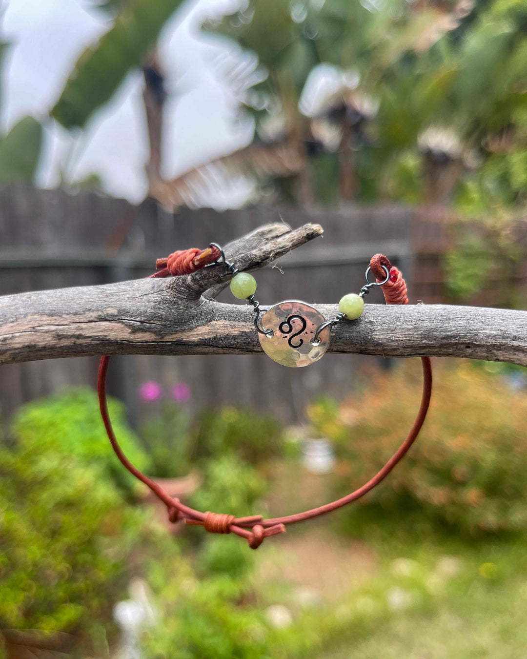 Leo zodiac bracelet with peridot beads on caramel leather shown outdoors