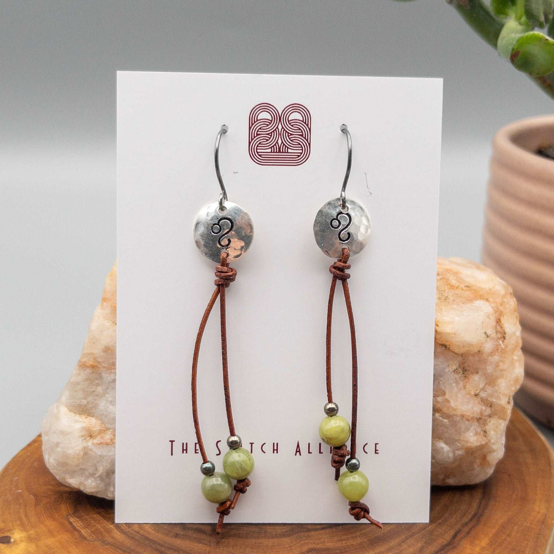 Sterling silver Leo stamped earrings with peridot beads on long leather cord. 