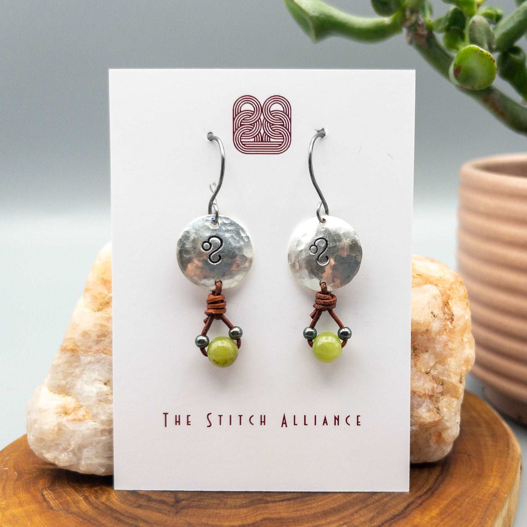 Leo sign stamped sterling silver earrings with peridot beads on a white card
