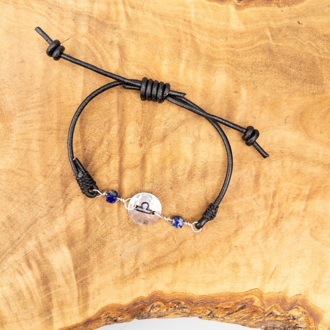 Libra bracelet with lapis lazuli beads on a black leather adjustable strap on a wood background