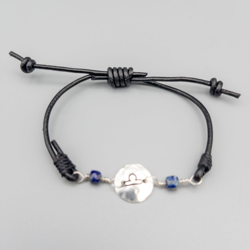 Libra bracelet with lapis lazuli beads on a black leather adjustable strap on a gray background