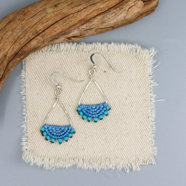 light blue, handmade triangle hoop earrings in sterling silver on an off white background