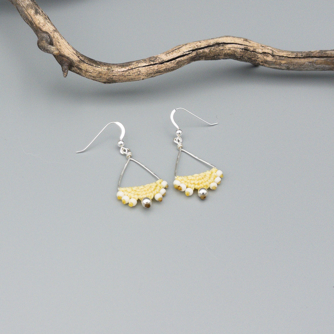 yellow macrame triangle hoop sterling silver earrings on a gray background