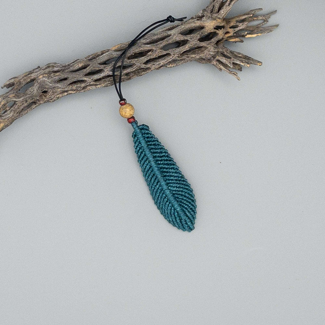 large teal macrame feather on gray background