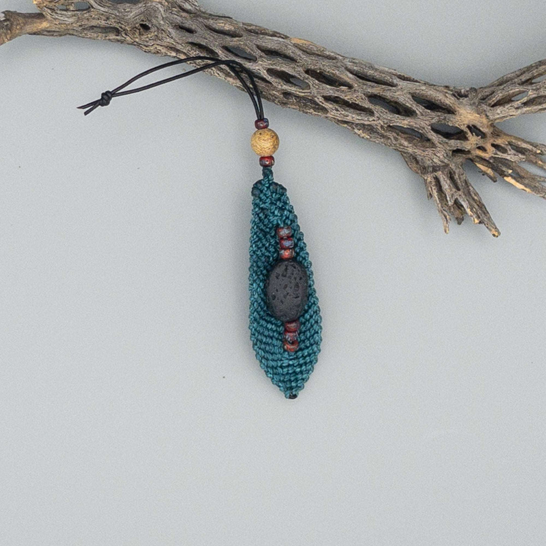 back of large teal macrame feather on gray background