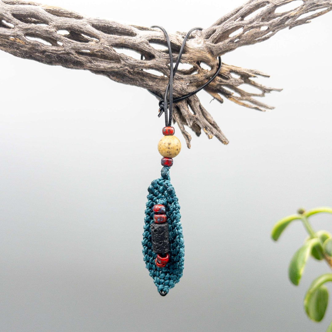 back of small teal macrame feather hanging from cholla branch