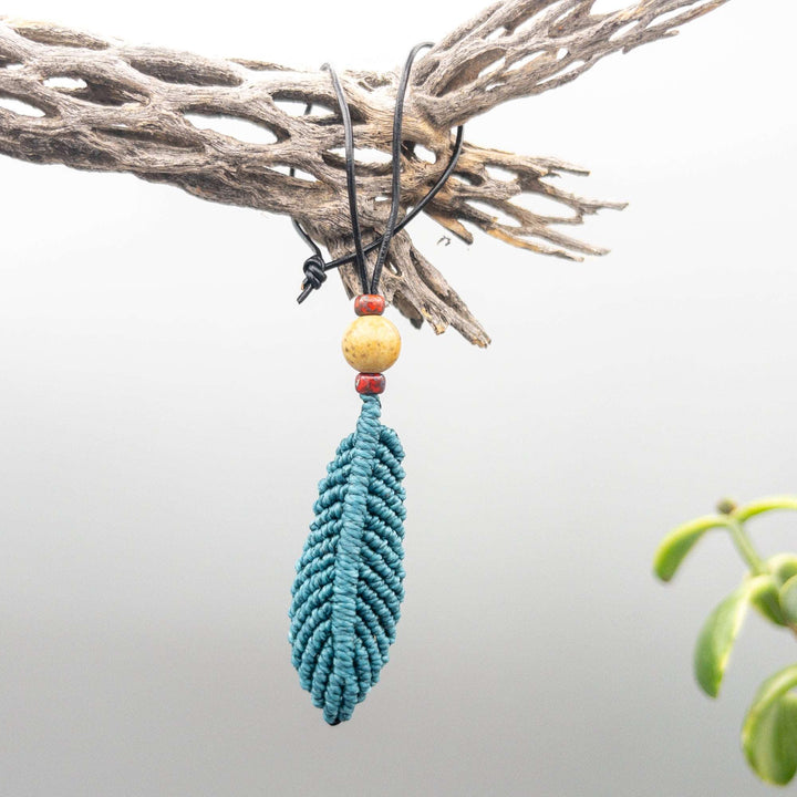 small teal macrame feather hanging from cholla branch
