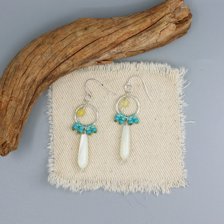 handmade sterling silver, mother of pearl and yellow opal macrame earrings on an off white background