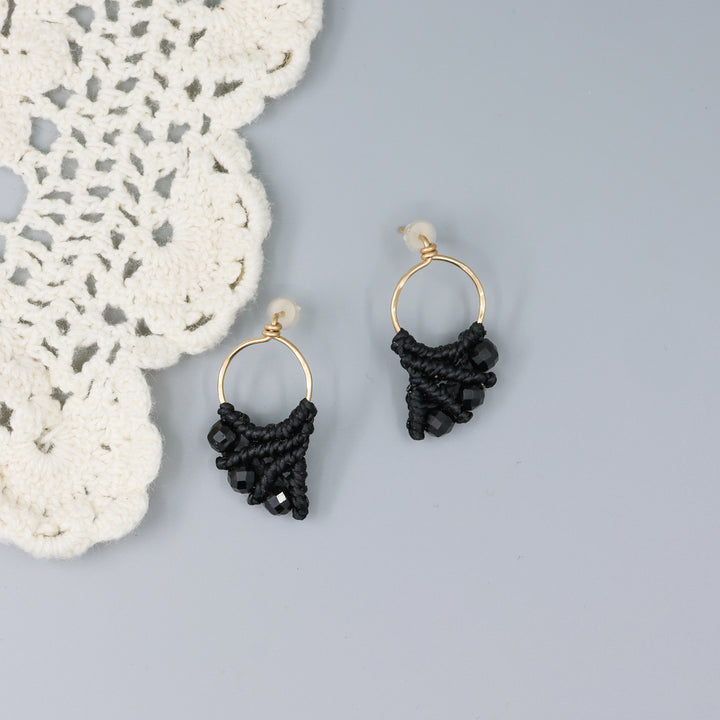 handmade gold fill macrame earrings with black spinel beads on a gray background