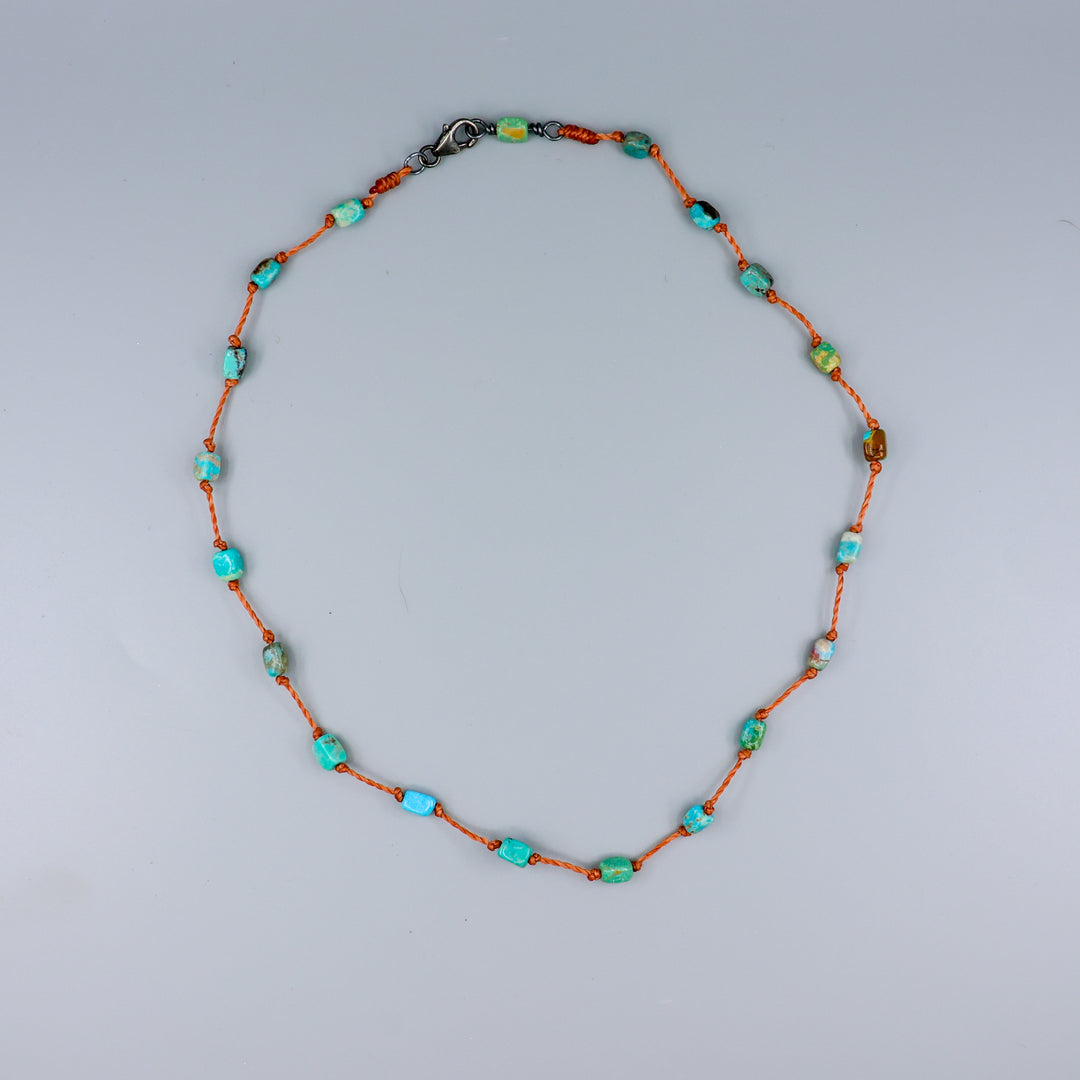 overhead view of a Handmade turquoise bead necklace on hand knotted terracotta cord with an oxidized sterling silver clasp