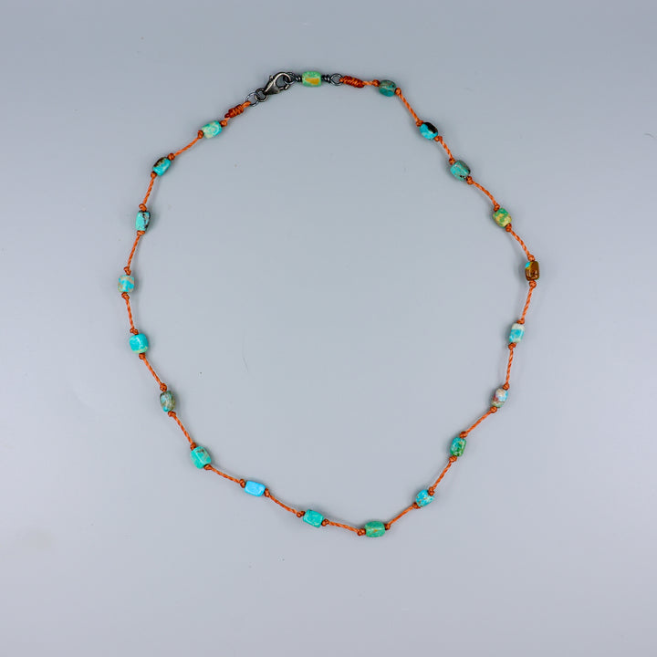 overhead view of a Handmade turquoise bead necklace on hand knotted terracotta cord with an oxidized sterling silver clasp