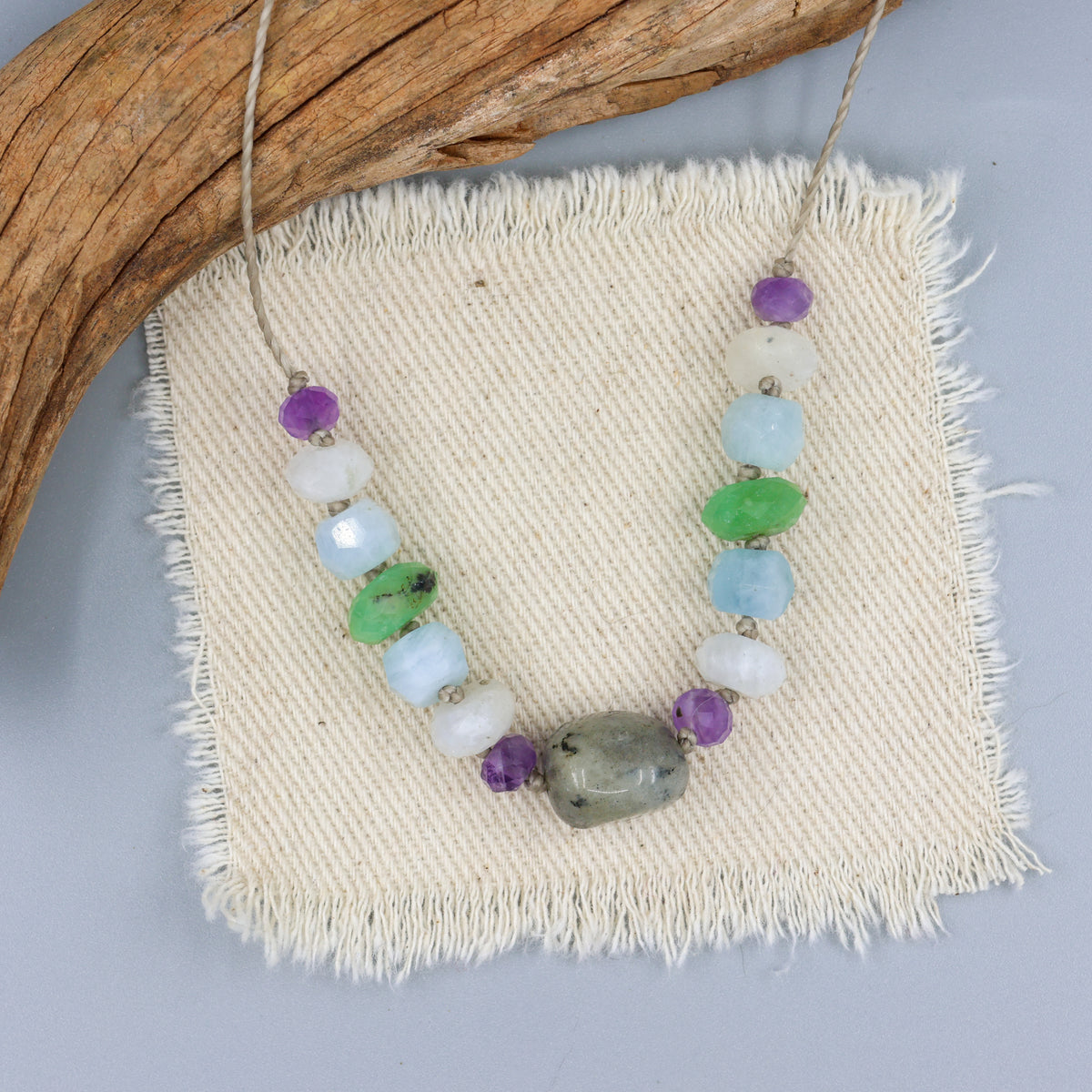 labradorite, amethyst, moonstone, aquamarine, and chrysoprase hand-knotted necklace on an off white background