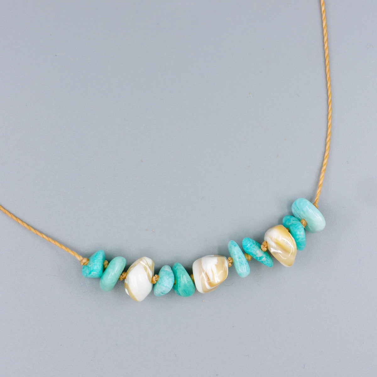 handknotted mother of pearl and amazonite beach inspired necklace with a gold clasp on a gold colored cord