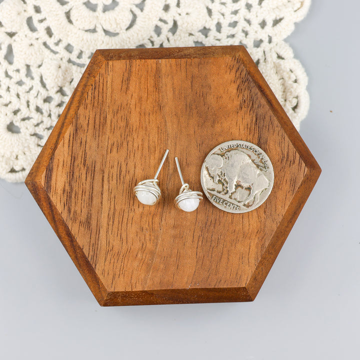 handmade moonstone and sterling silver wire wrapped stud earrings with a nickel for size comparison