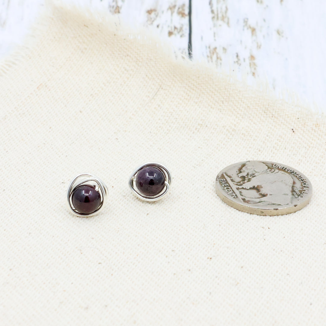 handmade wire wrap sterling silver garnet stud earrings shown with. a coin for size comparison