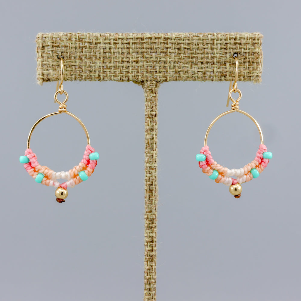 handmade round gold hoops with macrame deatils in coastal sunset colors on a linen hanger