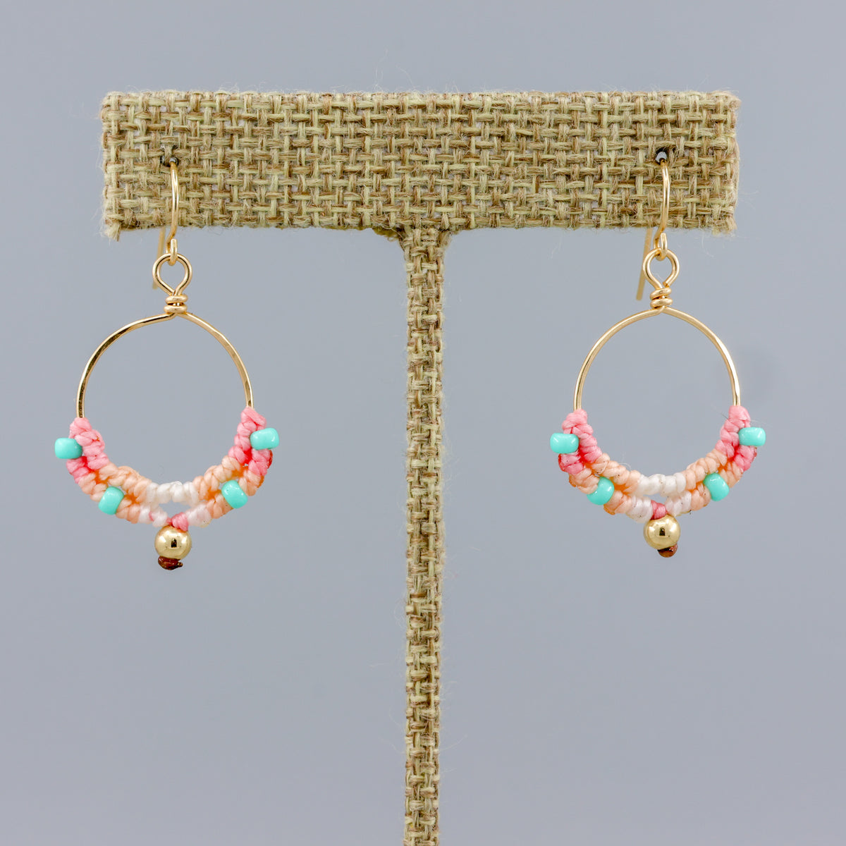 handmade round gold hoops with macrame deatils in coastal sunset colors on a linen hanger