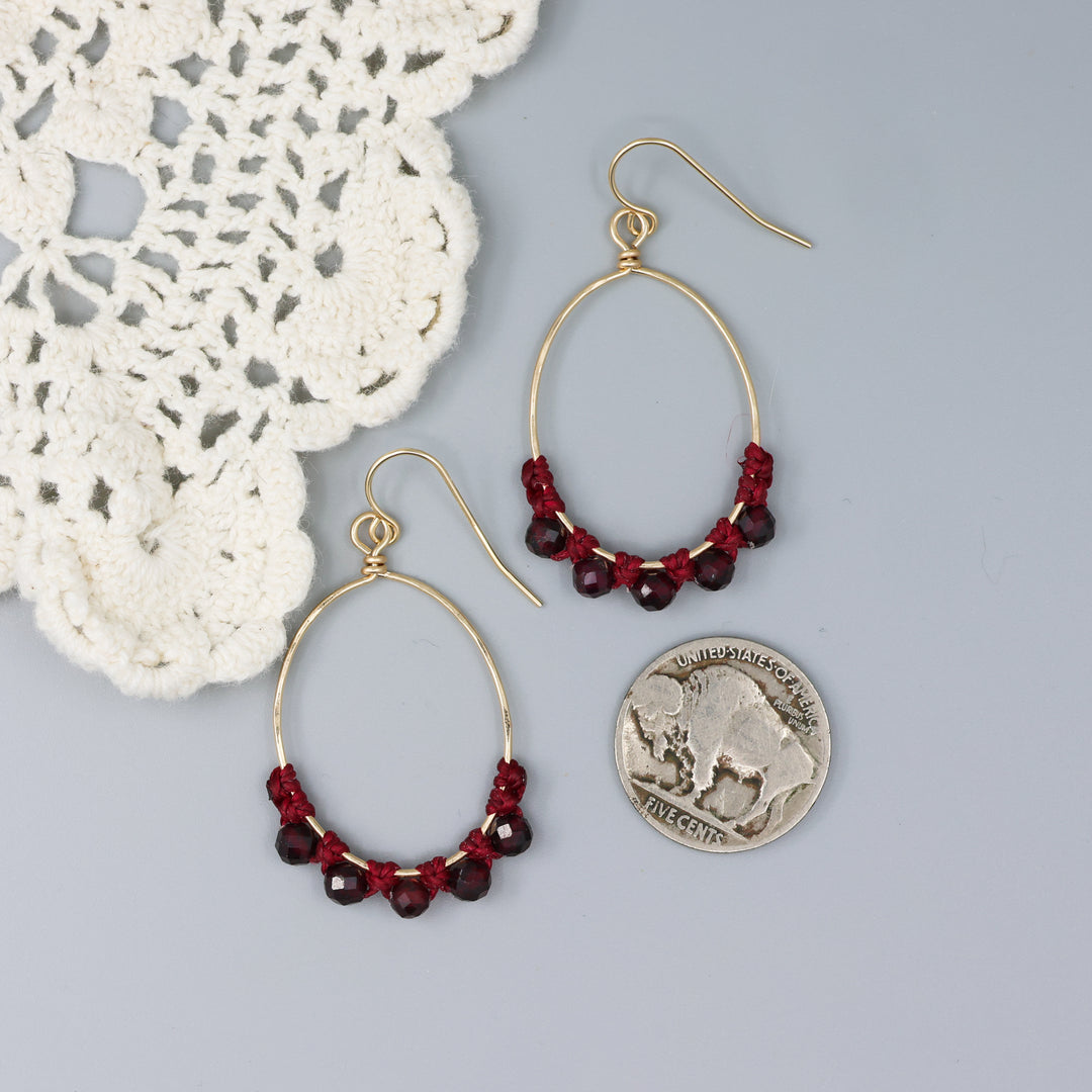handmade gold macrame hoop earrings with garnet beads with a nickel for size comparison