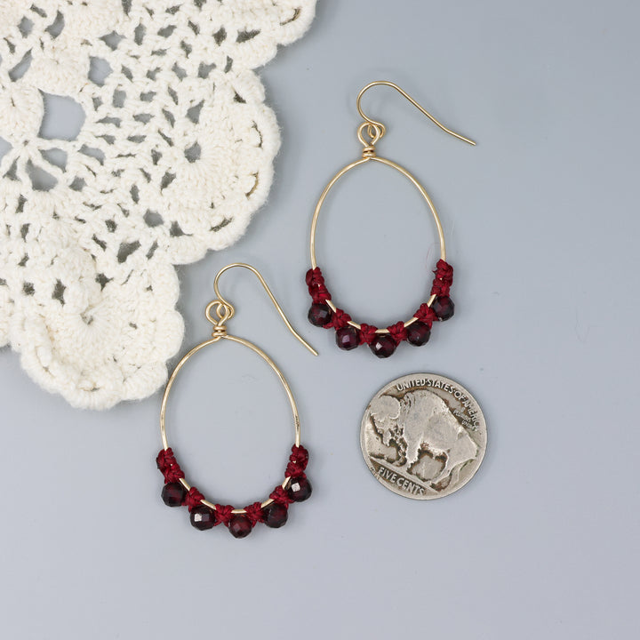handmade gold macrame hoop earrings with garnet beads with a nickel for size comparison