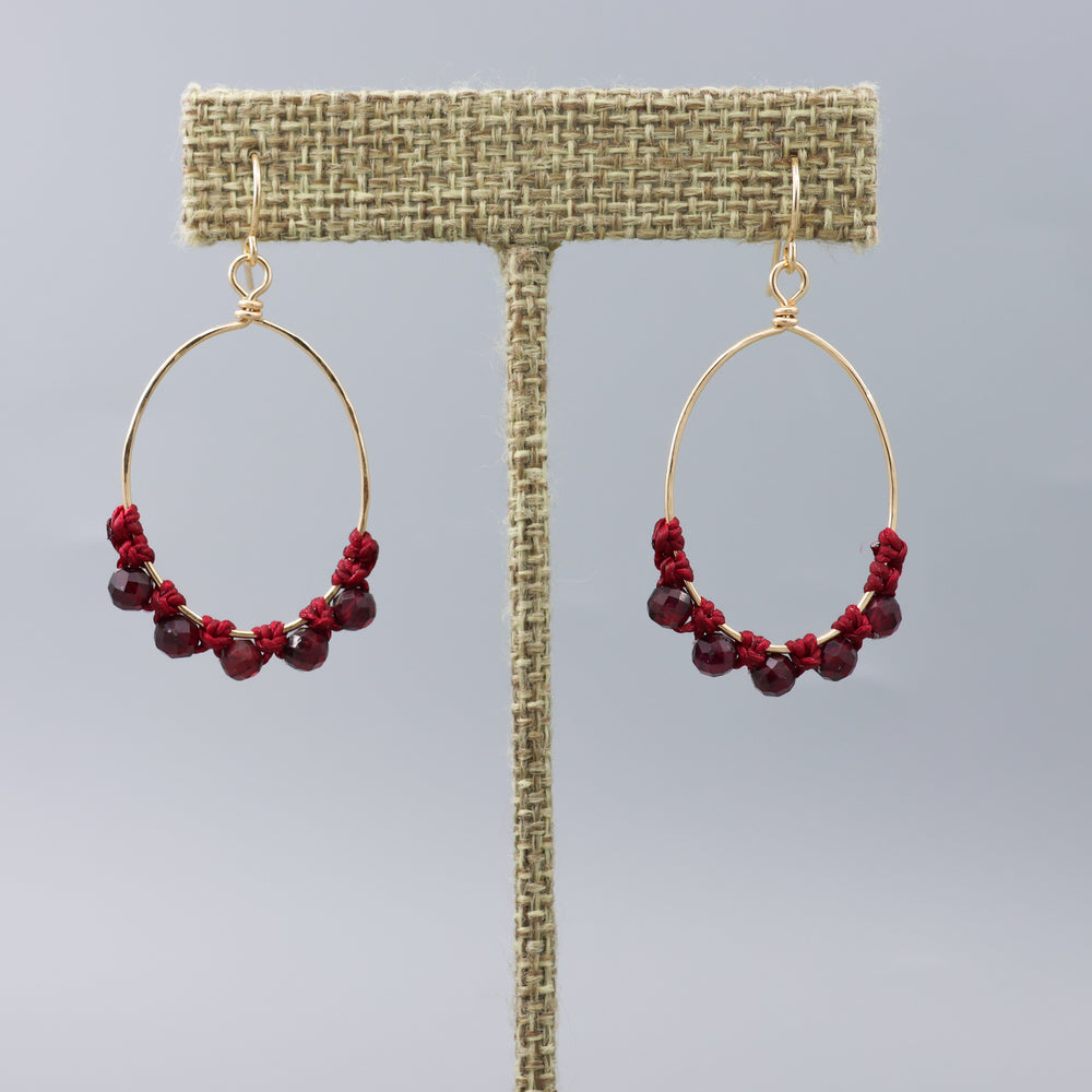 handmade gold macrame hoop earrings with garnet beads on a linen hanger