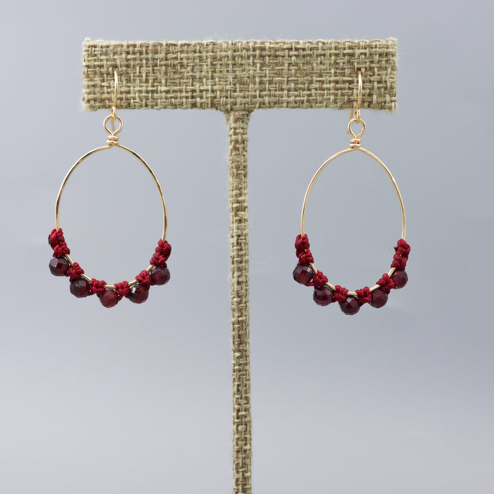 handmade gold macrame hoop earrings with garnet beads on a linen hanger