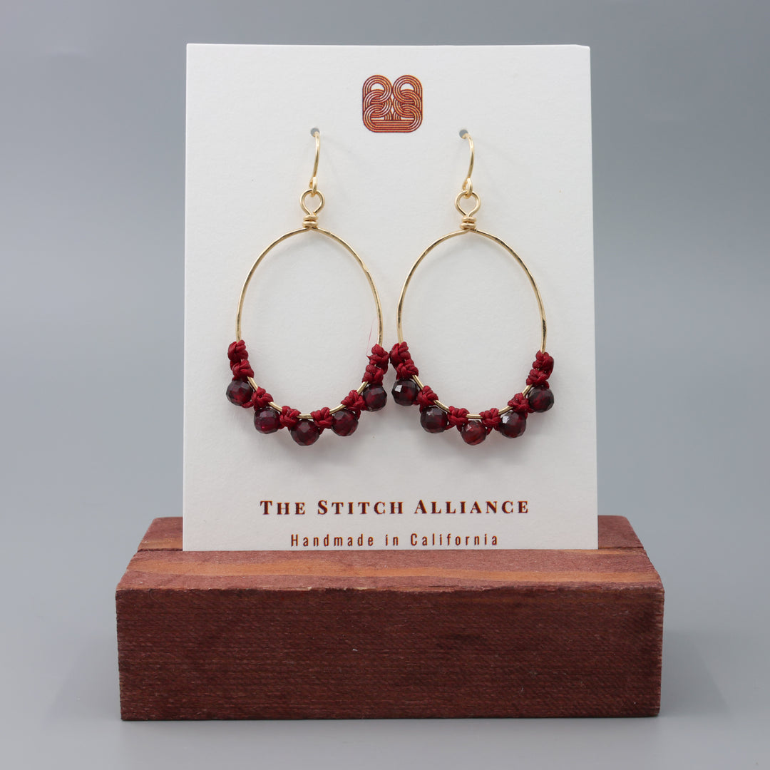 handmade gold macrame hoop earrings with garnet beads on a white card