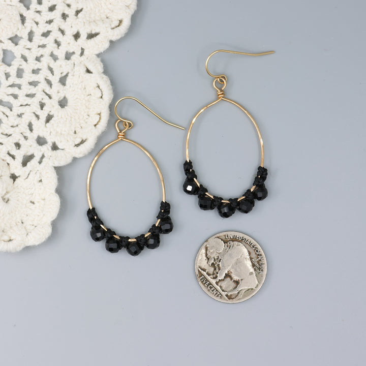 handmade gold hoops with black spinel beads and macrame with a nickel for size comparison