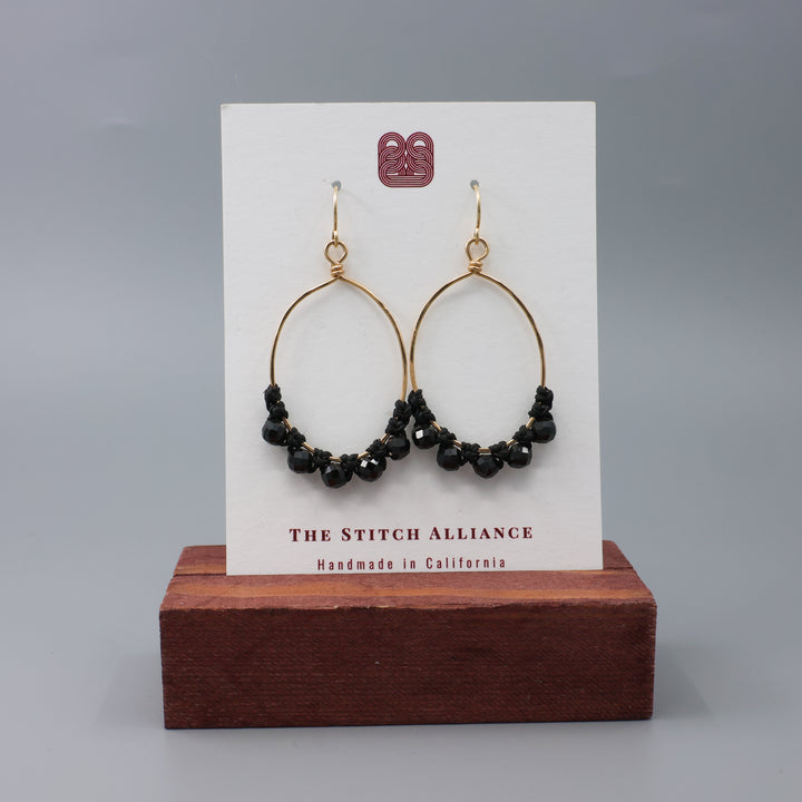 handmade gold hoops with black spinel beads and macrame on a white card