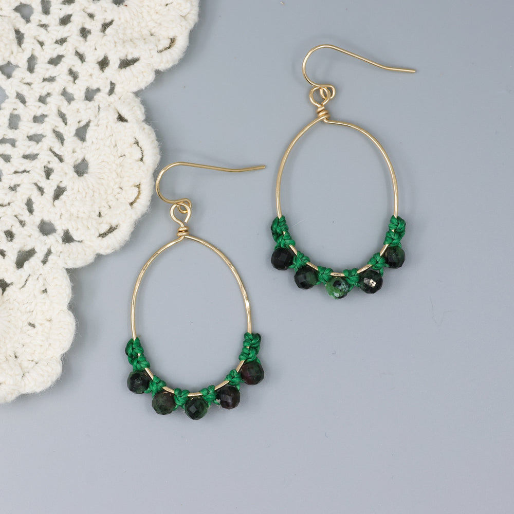 handmade gold hoop macrame earrings with ruby in zoisite beads on a gray background