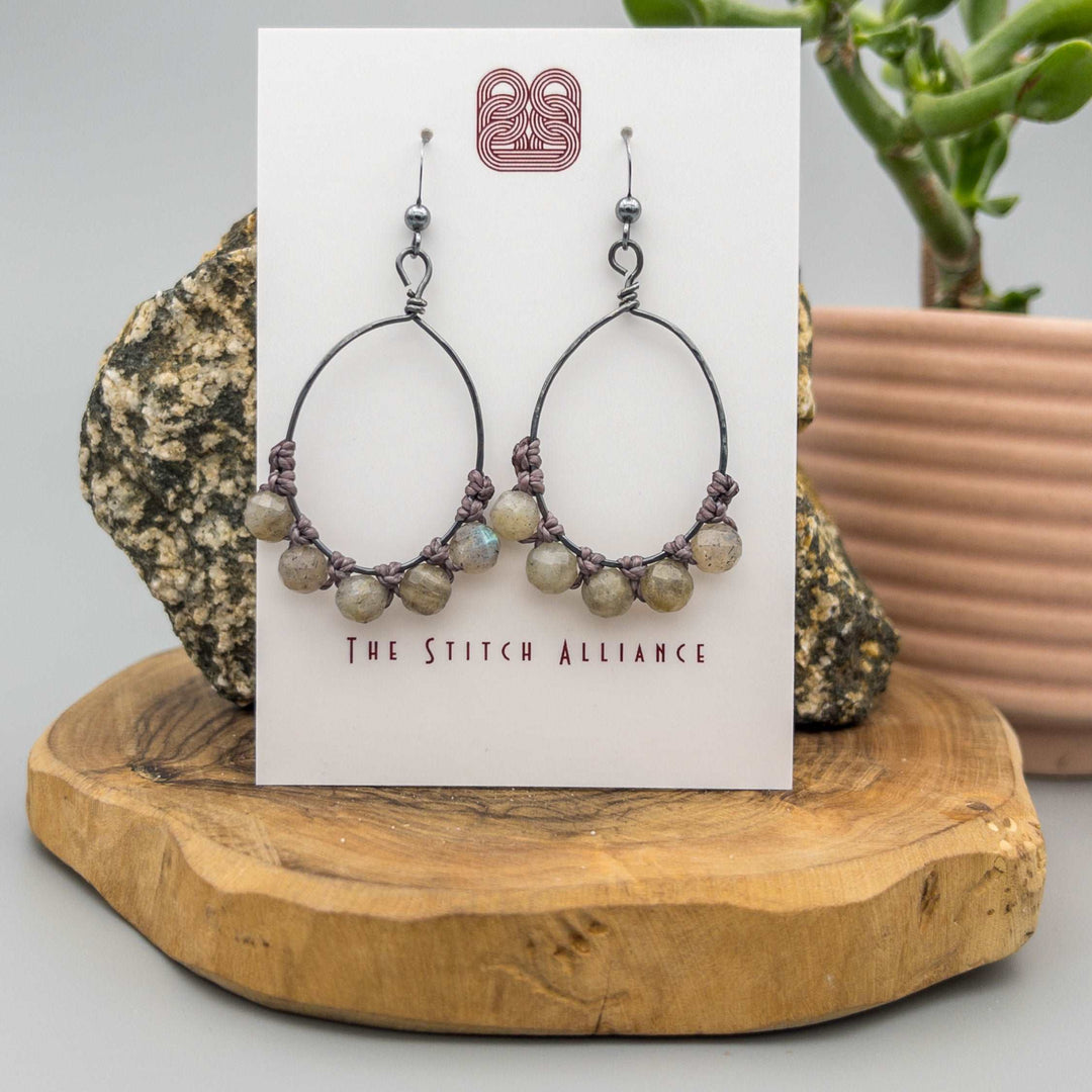 oxidized sterling silver oval hoop earrings with labradorite beads shown on a white background
