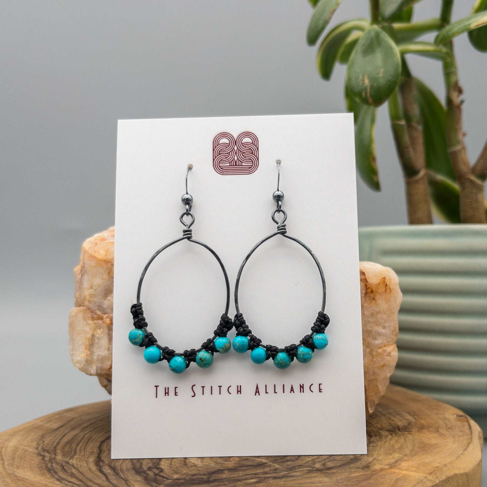 oxidized sterling silver oval hoop earrings with sea sediment jasper beads on a white background