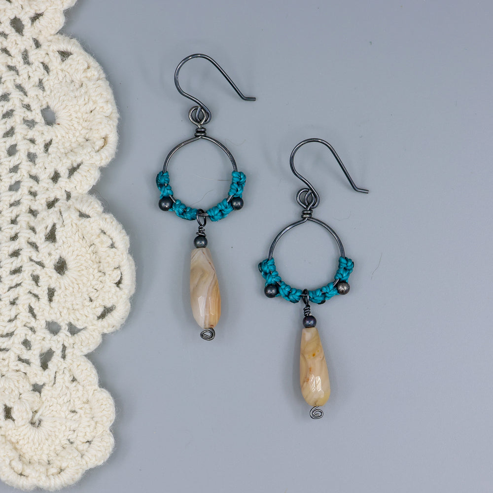 handmade macrame hoop earrings in oxidized sterling silver with botswana agate beads on a gray background