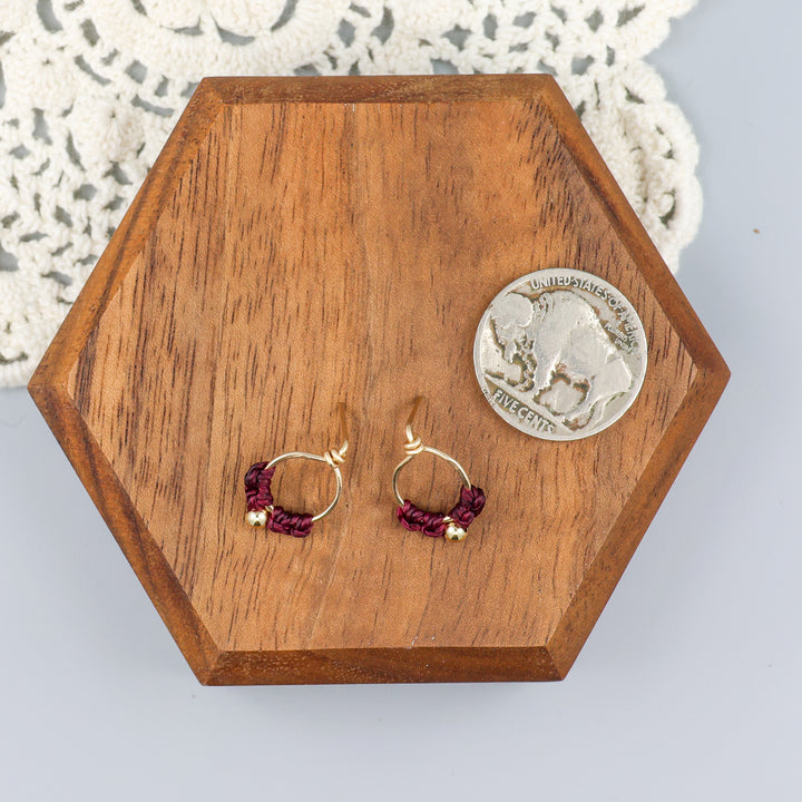 small, gold-filled macrame stud earrings with a coin for size comparison