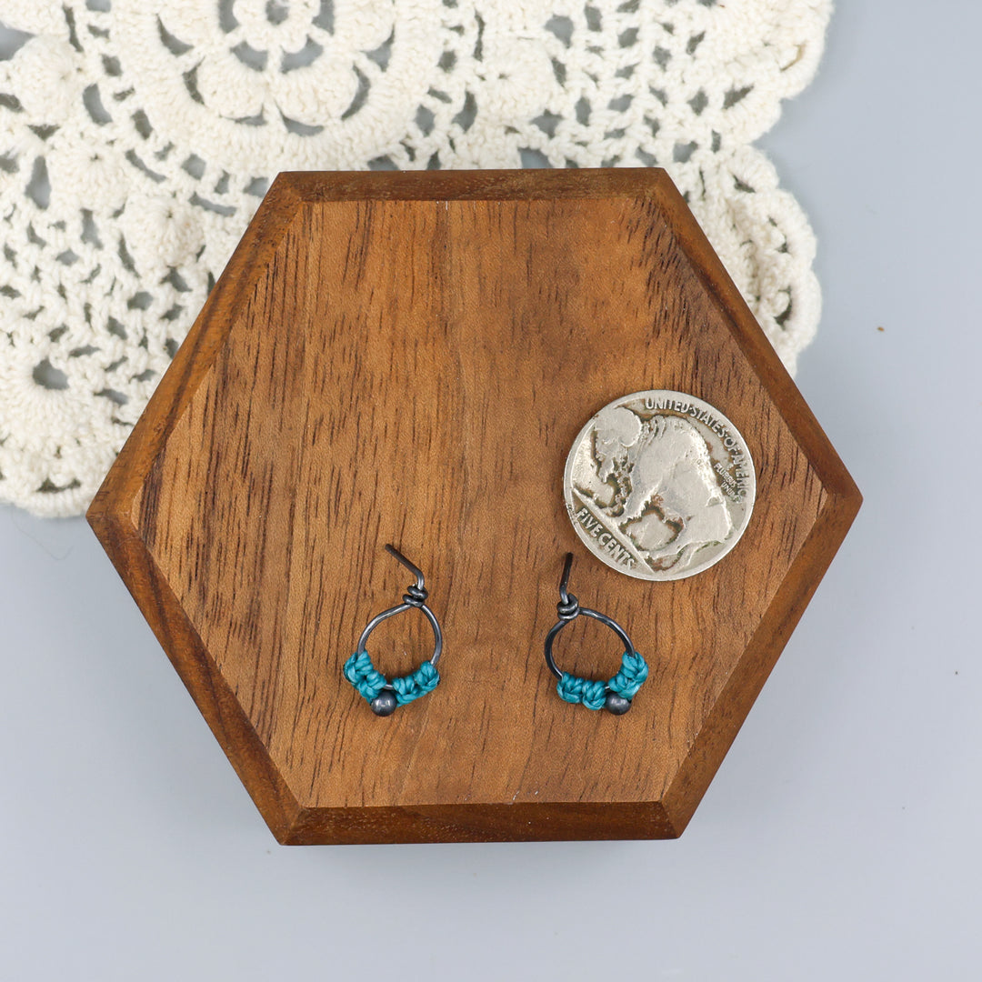small, oxidized sterling silver macrame stud earrings in turquoise with a coin for size comparison