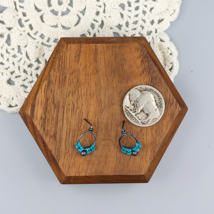 small, oxidized sterling silver macrame stud earrings in turquoise with a coin for size comparison