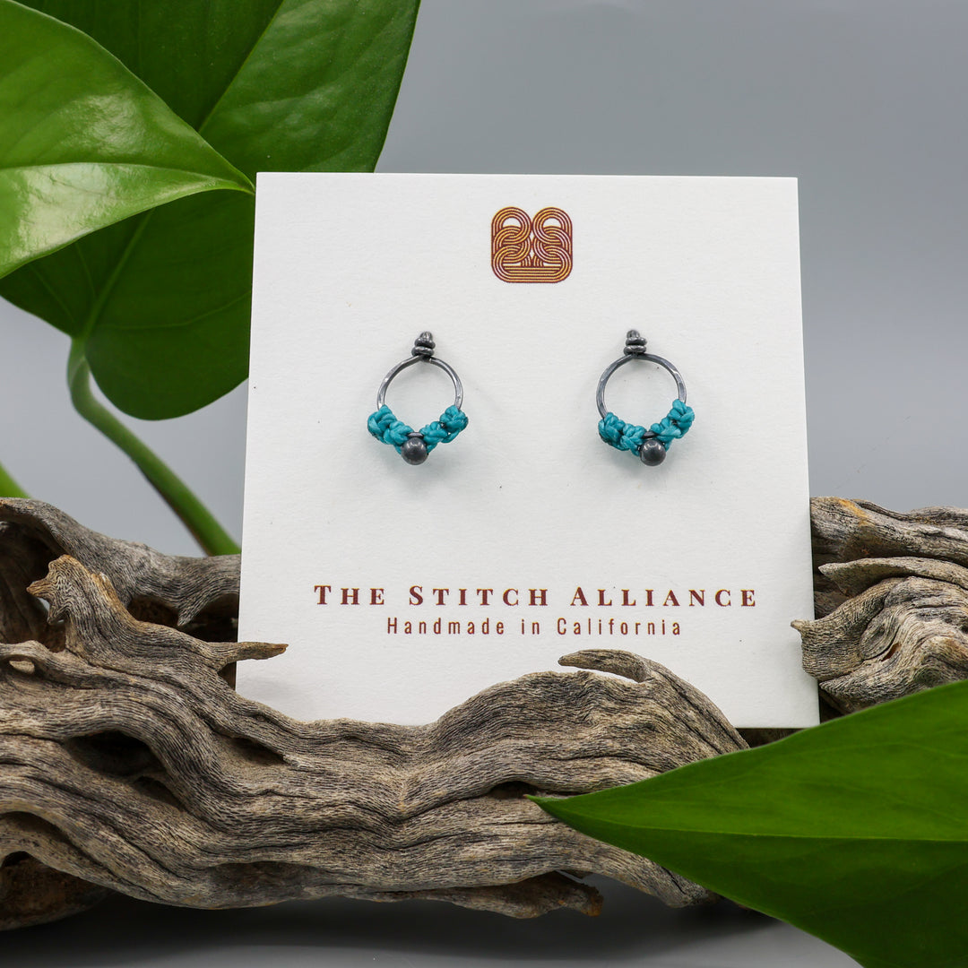 small, oxidized sterling silver macrame stud earrings in turquoise on a white card