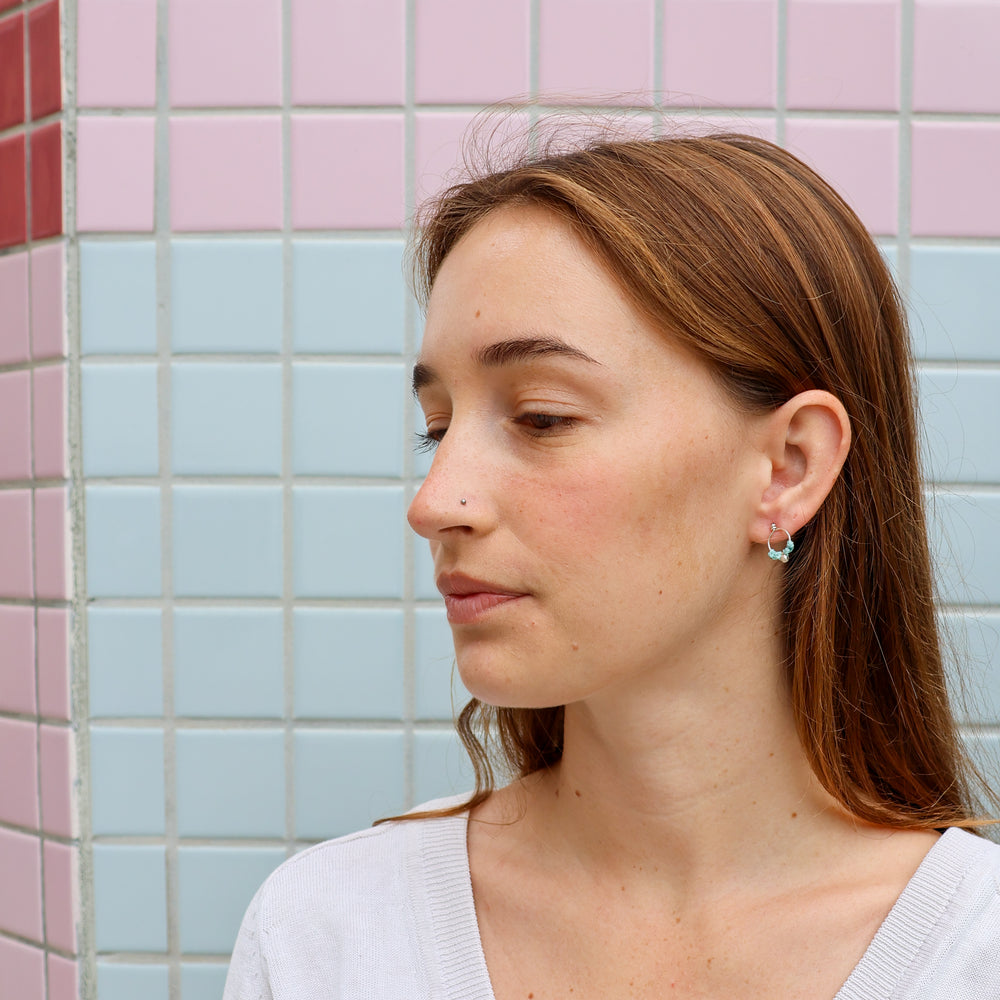 small, handmade sterling silver macrame earrings worn on a model