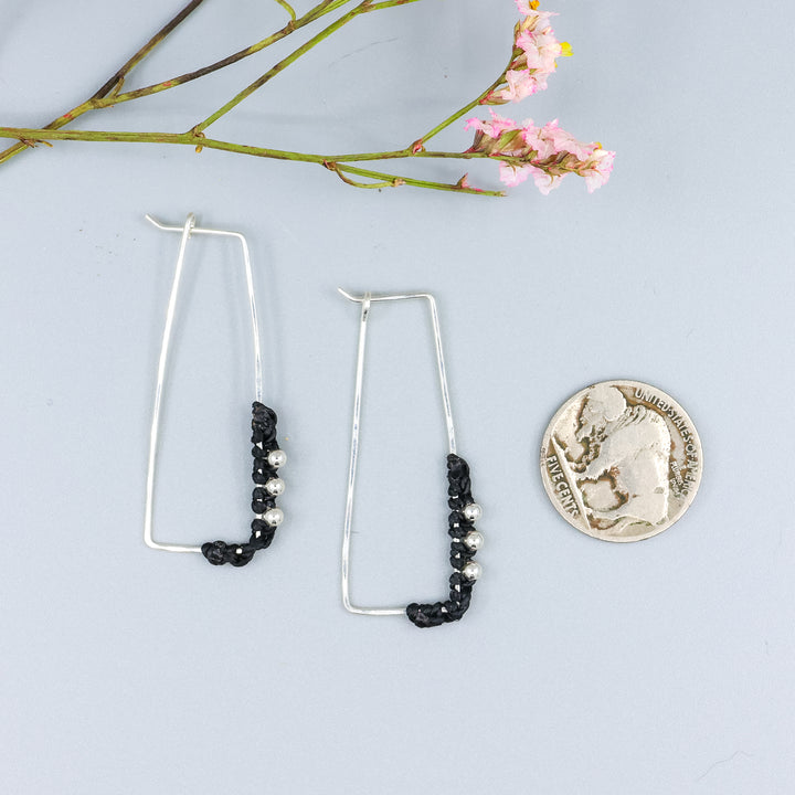 handmade sterling silver rectangle hoops with macrame detail with a nickel for size comparison