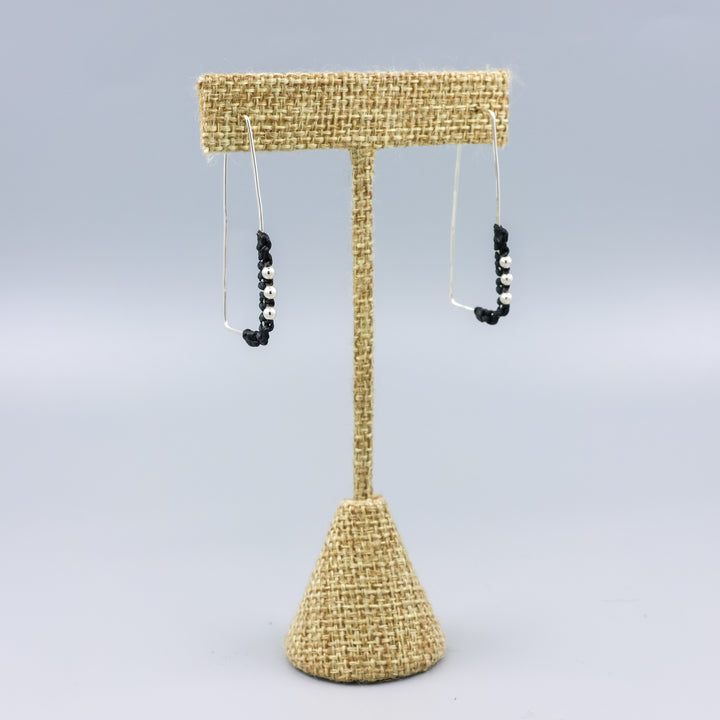 handmade sterling silver rectangle hoops with macrame detail on a linen hanger
