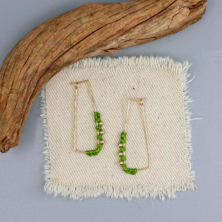 handmade macrame gold filled hoop earrings with green macrame and gold beads on an off white background