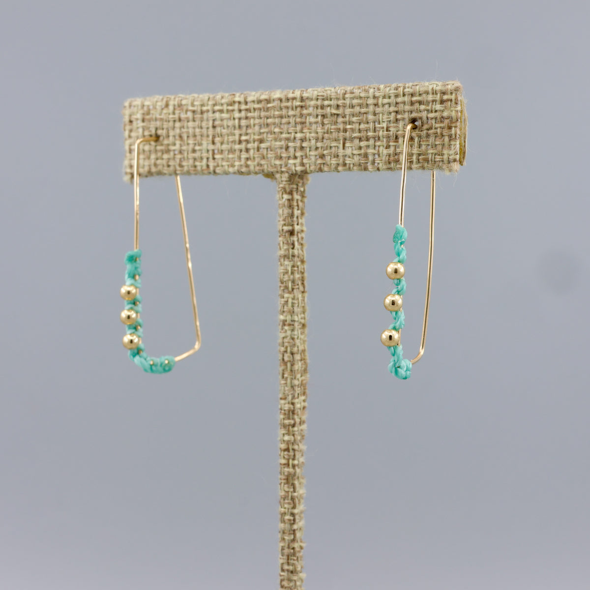 gold fill rectangle hoop earrings with seafoam macrame and gold beads on a linen hanger