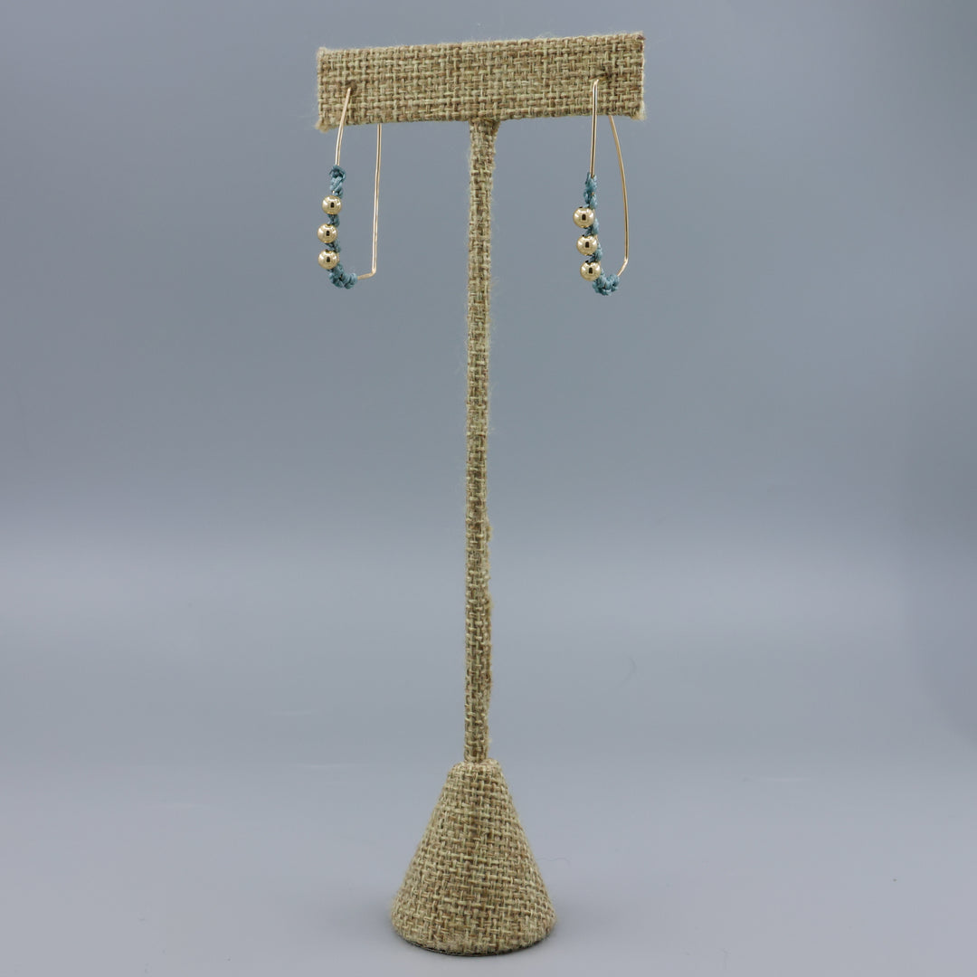 gold fill rectangle hoop earrings with macrame details on a linen hanger