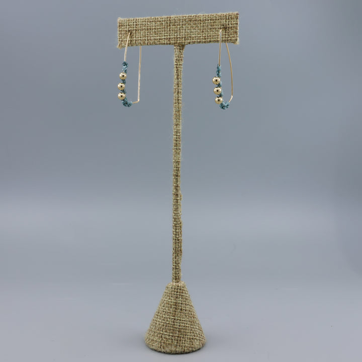 gold fill rectangle hoop earrings with macrame details on a linen hanger