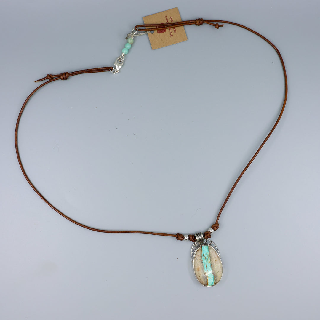 Ribbon turquoise sterling silver pendant on leather cord on a gray background