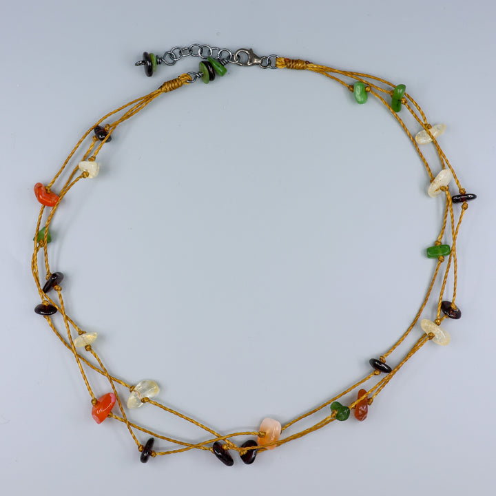 handknotted gemstone necklace with garnet, citrien, agate, and jade beads n a gray background