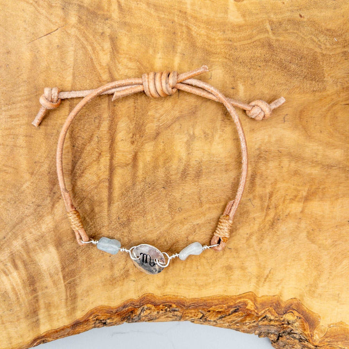 Scorpio zodiac sterling silver and  leather bracelet with aquamarine beads on a wood background